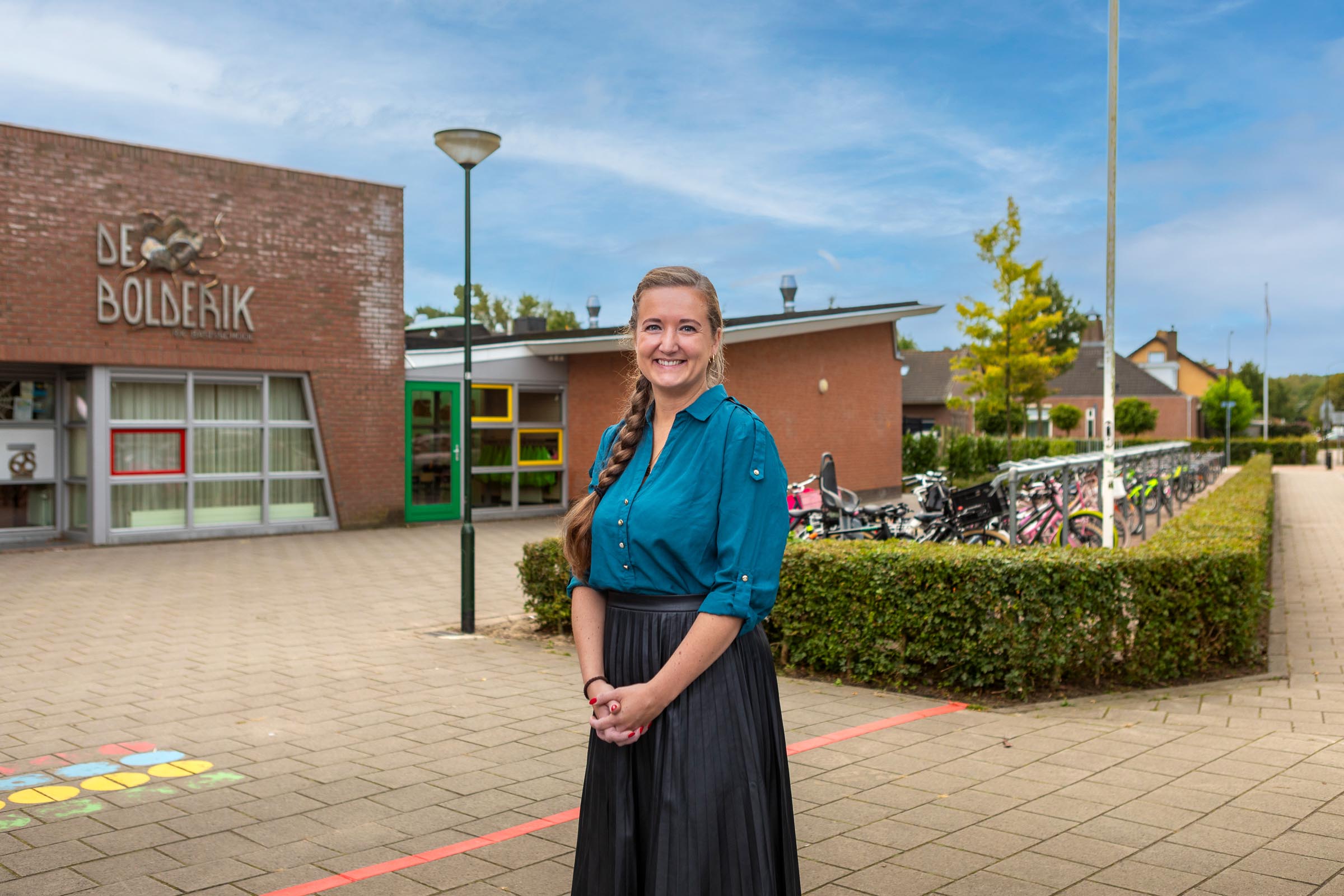 Foto van Ilona de Leeuw-Goedhart, directeur van De Bolderik, staande op het schoolplein voor het gebouw.